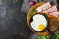 Scrambled.Fried eggs in a frying pan, bacon, rye bread, lettuce leaves, dark rustic background. Top view, copy space. Royalty Free Stock Photo
