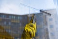 Scraper for washing windows in hands in yellow gloves.