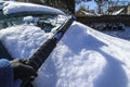 Scraping snow off of car windshield - hand in glove and telescoping ice scraper with shadows - selective focus