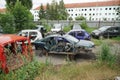 Scrapyard full of car carcasses in a provincial town in Eastern Europe surrounded by a fence of corrugated iron. Behind it there i Royalty Free Stock Photo