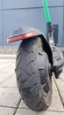 Scratched and damaged rear wheel of an electric scooter on a city street against the background of paving slabs. Old e-scooter