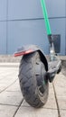 Scratched and damaged rear wheel of an electric scooter on a city street against the background of paving slabs. Old e-scooter