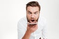 Screaming angry young bearded emotional man talking by phone. Royalty Free Stock Photo