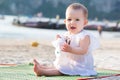 Screaming baby girl in white dress. Infant sitting on the sandy tropical beach Royalty Free Stock Photo