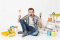 Screaming crazy man sitting on floor with brush, putty knife instruments for renovation apartment room isolated on white Royalty Free Stock Photo