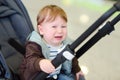 Screaming little baby boy portrait. Crying toddler is sitting in stroller. Kids hysterics. Difficult and problems of travel with