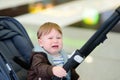 Screaming little baby boy portrait. Crying toddler is sitting in stroller. Kids hysterics. Difficult and problems of travel with Royalty Free Stock Photo