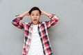 Screaming shocked young asian man over grey background