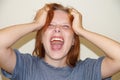 Screaming teen girl clutching her head with her hands, portrait Royalty Free Stock Photo