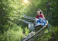 Screaming teen girl riding downhill on an outdoor roller coaster on a warm summer day.