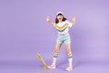 Screaming teen girl in vivid clothes standing with yellow skateboard spreading hands isolated on violet pastel wall Royalty Free Stock Photo