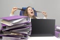 Screaming woman at desk with laptop and folders. Female entrepreneur suffers from nervous breakdown caused by fatigue, too much