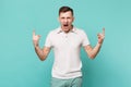 Screaming young man in casual clothes depicting horns up gesture, heavy metal rock sign isolated on blue turquoise Royalty Free Stock Photo