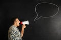 Screaming young man with megaphone near drawn speech bubble on dark background Royalty Free Stock Photo