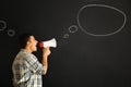 Screaming young man with megaphone near drawn speech bubble on dark background Royalty Free Stock Photo