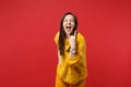 Screaming young woman in yellow fur sweater with horns up gesture, depicting heavy metal rock sign isolated on bright Royalty Free Stock Photo