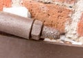 Screed bolt brown swirling nut long stem piece of construction metalwork weathered old on brick wall background loft style grunge Royalty Free Stock Photo