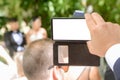 Screen with copy space of a mobile phone held by the hand of a guest who is recording the wedding of a wedding couple outdoors in