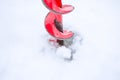 of ice drill, painted with red paint, it cuts into ice and snow in lake or river. Drilling holes in ice - winter fishing sce