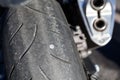 Screw nail puncturing motorcycle tire. Close up view at rear wheel
