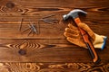 Screw nails, hammer and glove on wooden background
