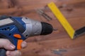 Screwdriver in hand close-up. Blurred wooden background
