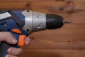 Screwdriver in hand close-up. Blurred wooden background