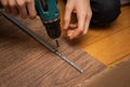 Screwdriver in male hands screwing in screws to stick steal detail part to board. Assembling piece of furniture at home