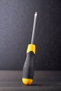 Screwdriver with rubber handle on dark background.