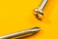 Screwdriver with screw on a yellow background