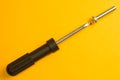 Screwdriver with screw on a yellow background