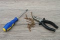 Screwdriver, Screws and Pliers on Wooden Table