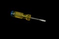 Screwdriver with a yellow and blue handle isolated on a black background Royalty Free Stock Photo