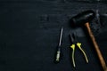 Screwdrivers, hammer, pliers and tools on a black wooden table. Top view
