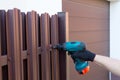 Screwing roofing screws into a metal picket fence by using cordless electric screwdriver. Royalty Free Stock Photo