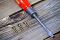 Screws and old screwdriver with a red wooden handle Royalty Free Stock Photo