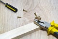 Screws, pliers and wooden bar on the table. Royalty Free Stock Photo