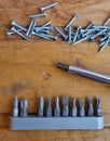 Screws, screwdriver and set of bits (heads) on wood background Royalty Free Stock Photo