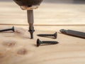 Screws twisted into a wooden board with an electric screwdriver, drills, screws close-up, home Royalty Free Stock Photo