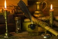 Scroll documents, burning candles, old books, an inkwell with a pen and an hourglass are on the table Royalty Free Stock Photo