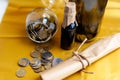 Scroll of paper with wine bootle and glass with coins on yellow background Royalty Free Stock Photo