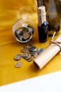 Scroll of paper with wine bootle and glass with coins on yellow background