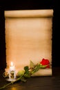 A scroll of parchment, a red rose and a lit candle