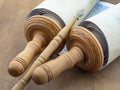 A scroll of Torah and a pointer on a wooden table, closeup.