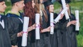 Scrolls of diplomas in the hands of a group of graduates.