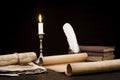 Scrolls of parchment and old papers and books on the background of a lit candle and inkwell pen Royalty Free Stock Photo