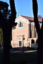 Scrovegni Chapel, illuminated by the sun, with pine trees in the shade and with the background of the blue sky in Padua.