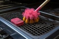 scrub brush and cleaning solution on oven grates