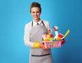 Scrubwoman with basket with detergents and brushes on blue