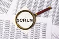 Scrum word through magnifying glass over financial business documents. Concept of modern methods in management